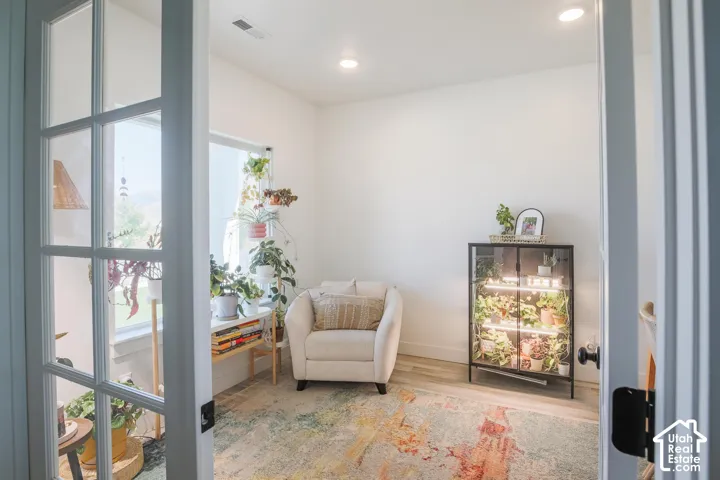 Double French doors with clear glass panels open to a room with light wood-finish flooring and recessed lighting