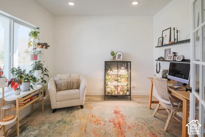 Recessed lighting, wood-finish flooring, white walls, large window, and French doors