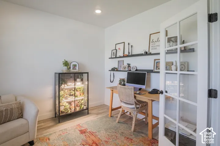White painted walls, wood-finish flooring, recessed ceiling lighting, and built-in wall shelving