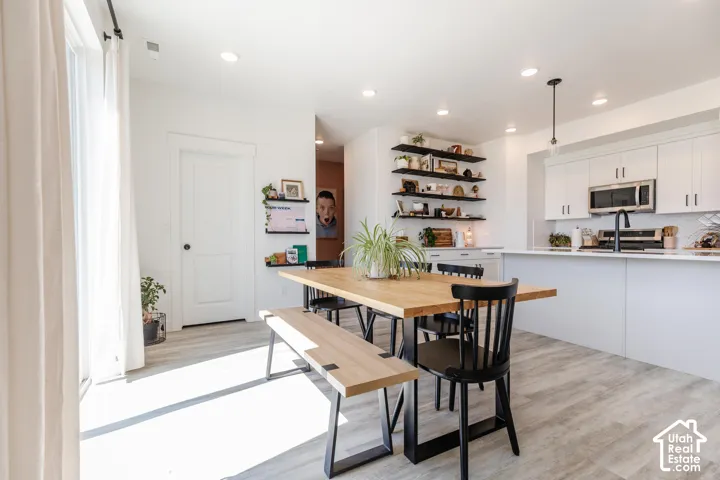 Modern kitchen featuring white cabinetry with brushed nickel hardware, stainless steel microwave, black faucet, and white subway tile backsplash