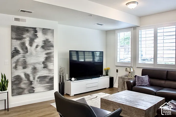 Recessed lighting, wood-finish flooring, white plantation shutters, and a modern media console