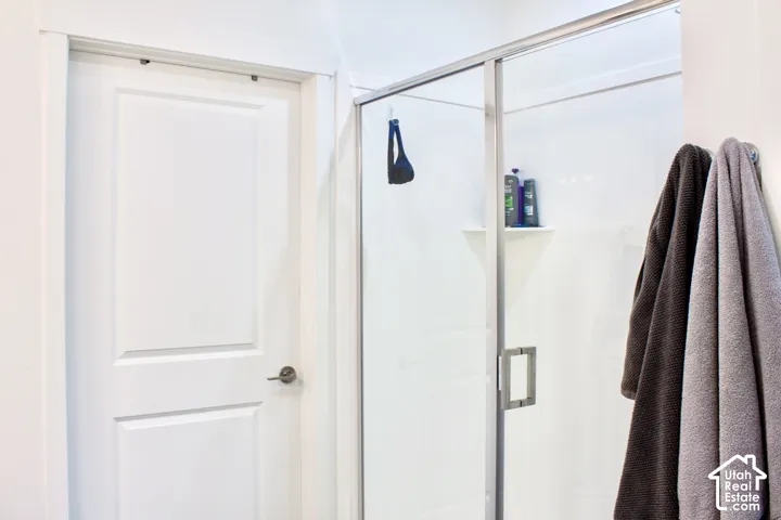 Shower enclosure with clear glass door, brushed nickel hardware, and an integrated corner shelf