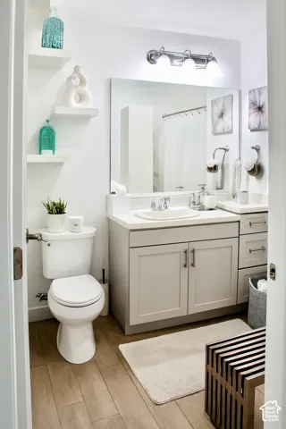Floating shelves, wood-finish flooring, vanity with integrated sink, chrome lighting fixture, and a built-in shower enclosure