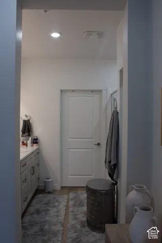 Recessed ceiling lighting, wood-finish flooring, white paneled door, light gray cabinetry, and a light-toned countertop