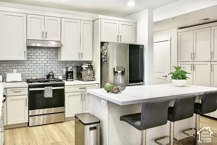 Light-toned cabinetry, stainless steel range, and subway tile backsplash