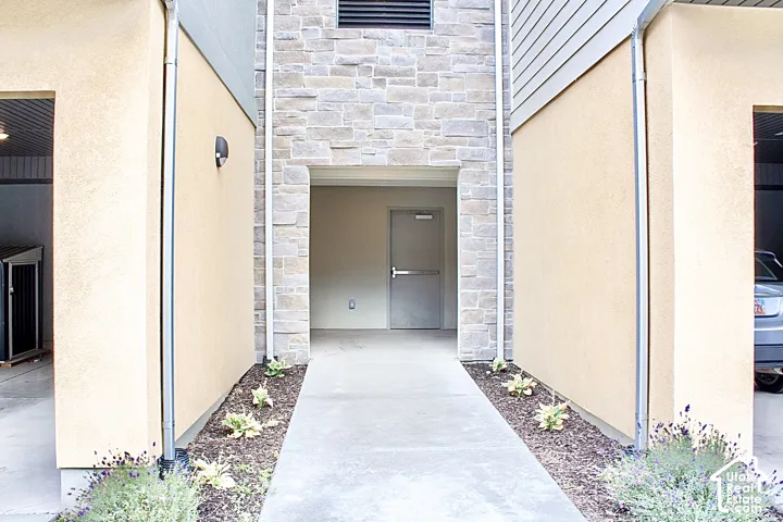 Entryway featuring a concrete walkway, decorative stone accents, stucco siding, and a security door