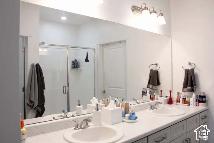 Double vanity with integrated sinks, brushed nickel fixtures, under-cabinet storage, and an expansive wall-mounted mirror