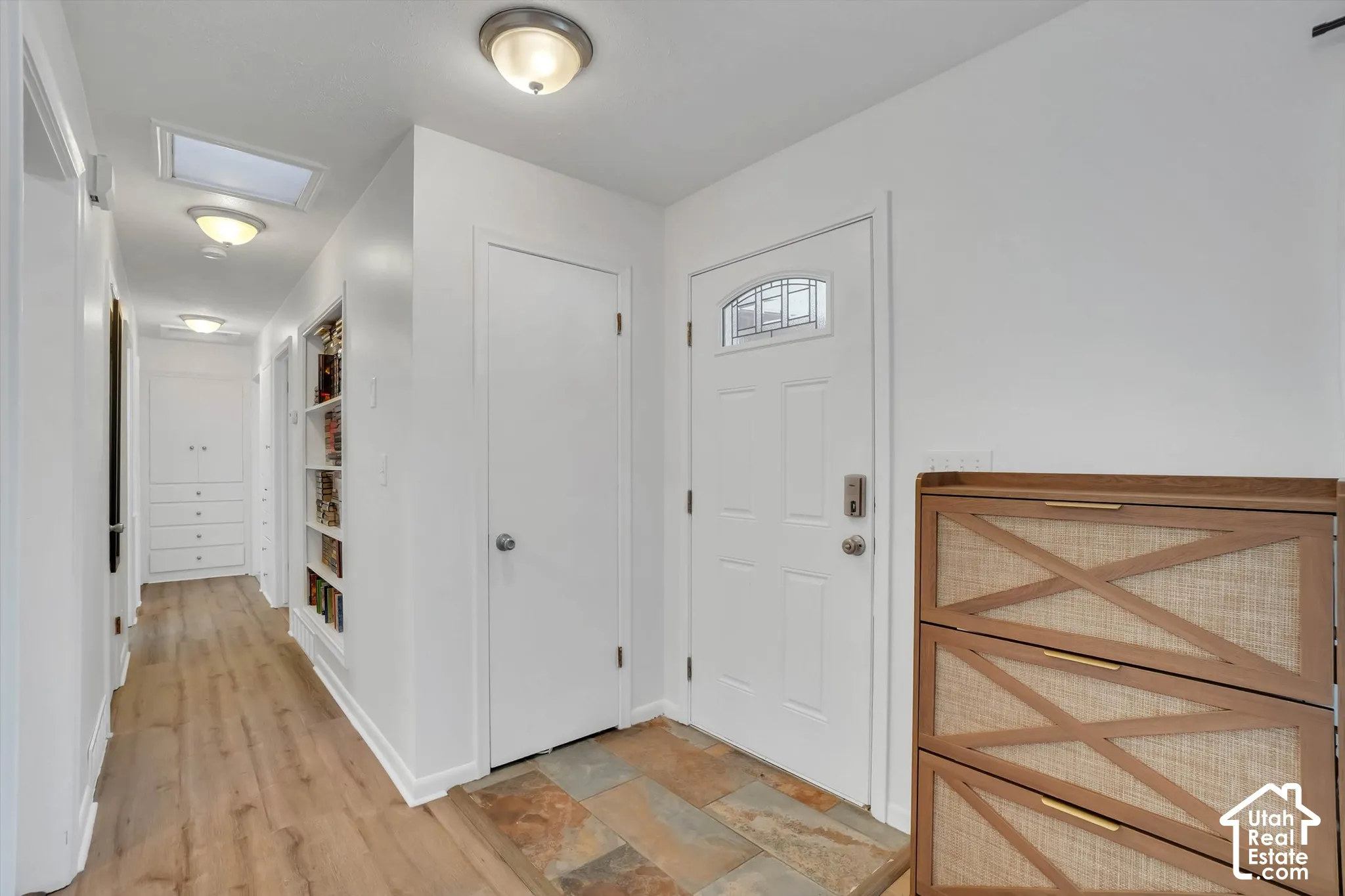 Entryway featuring a decorative glass panel door, slate tile flooring, and wood-finish flooring extending into the hall