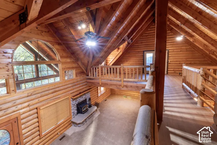 Vaulted wood-paneled ceilings, exposed wood beams, stone fireplace, wood-finish flooring, and an elevated walkway