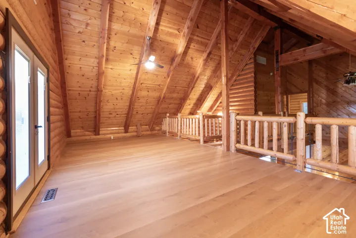 Open loft featuring wood-finish flooring, exposed wood beams, and a wood-paneled ceiling
