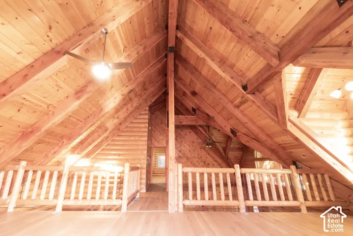 Vaulted wood-paneled ceiling with exposed beams, wood-finish flooring, and wood railing