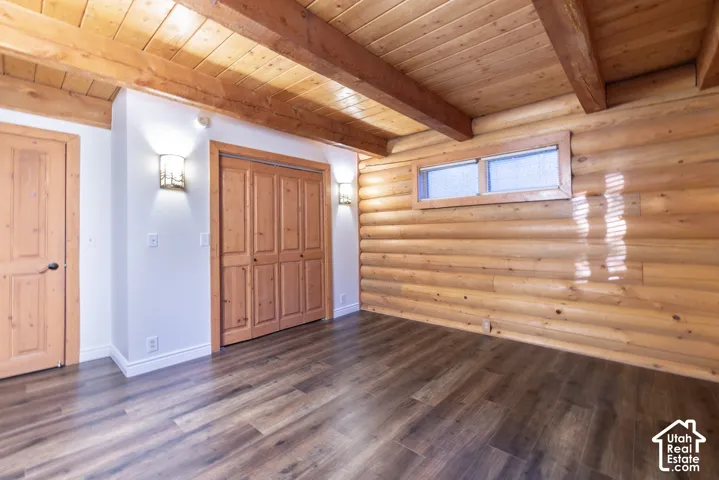 Wood-finish flooring, exposed wood beam ceiling, wood plank ceiling, log wall construction, and wood panel doors