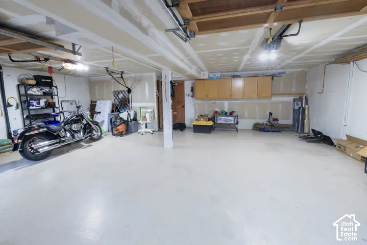 Unfinished basement with open ceiling joists, concrete flooring, and suspended overhead lighting