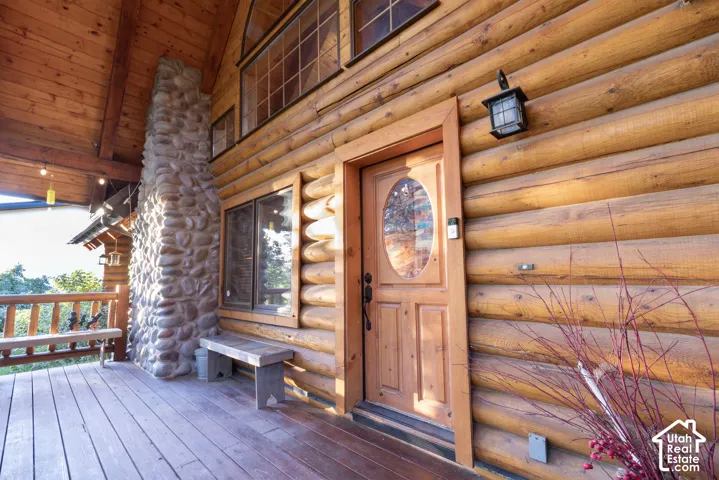 Log exterior construction with a wood porch, featuring a stone-clad chimney and a wood entry door with an oval glass insert