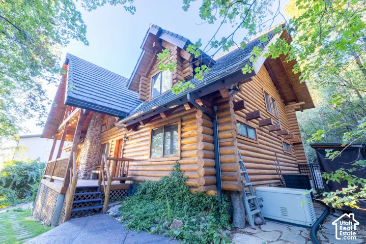 Log cabin exterior featuring a stone chimney, extensive wood siding, and gabled rooflines