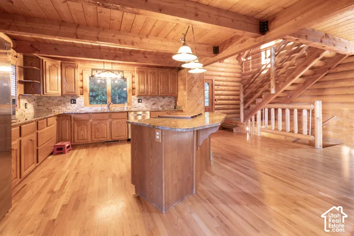 Open-concept kitchen featuring wood cabinetry, stone-finish countertops, and a full tile backsplash