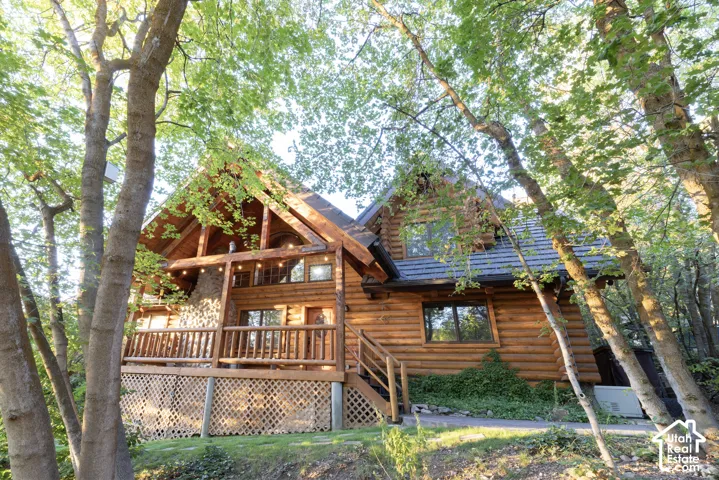 Log cabin exterior featuring a pronounced A-frame architectural style and a multi-level deck with wood railings