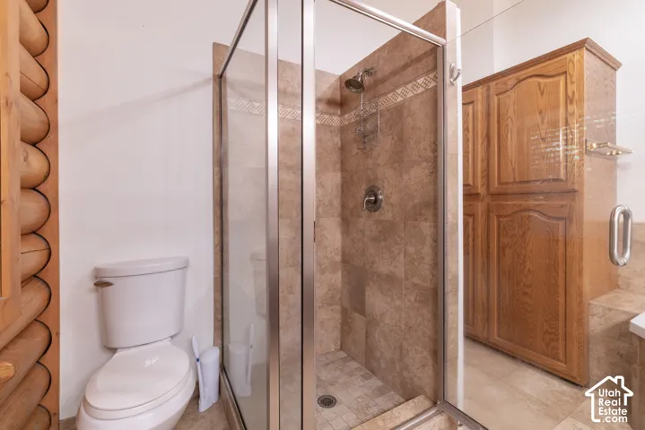 Glass-enclosed shower with tiled walls and flooring
