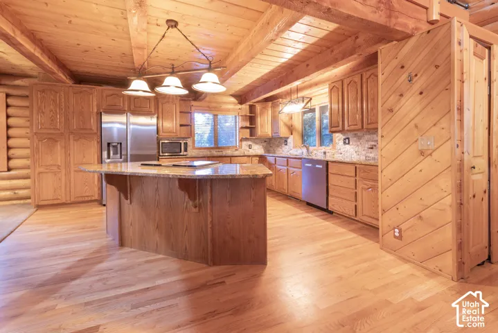 Wood-finish flooring, wood-paneled ceiling with exposed beams, wood cabinetry, granite countertops, and stainless steel appliances