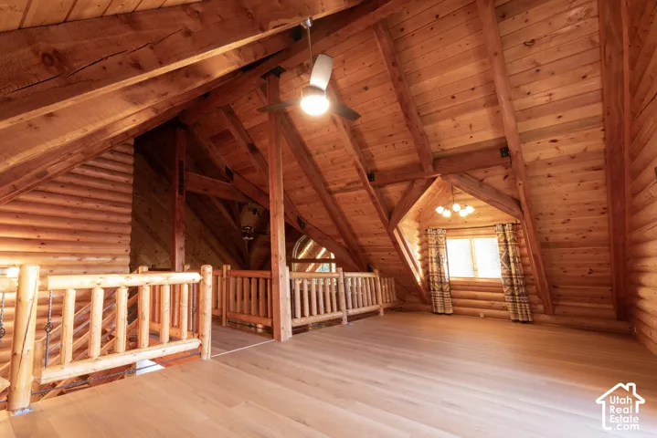 Vaulted wood-paneled ceiling, exposed wood beams, wood-finish flooring, wood log walls, and wood railing