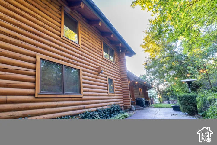 Log cabin exterior with multiple windows, an exterior light fixture, and a concrete pathway