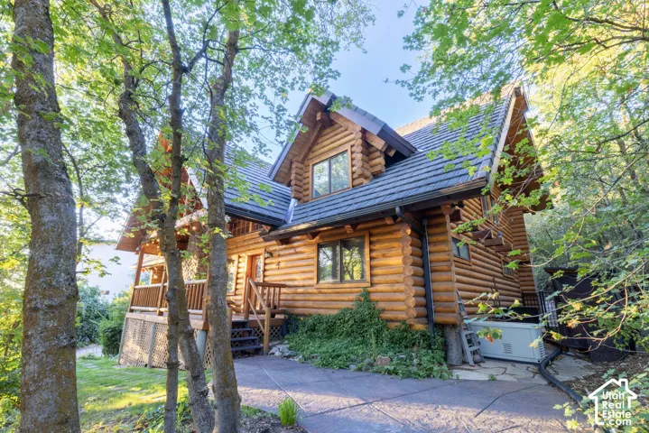 Log cabin exterior with a dark shingle roof, a covered porch, and exterior wood stairs