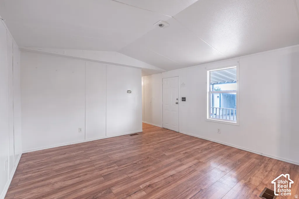 Wood-finish flooring, white walls, and a white ceiling with an angled architectural detail