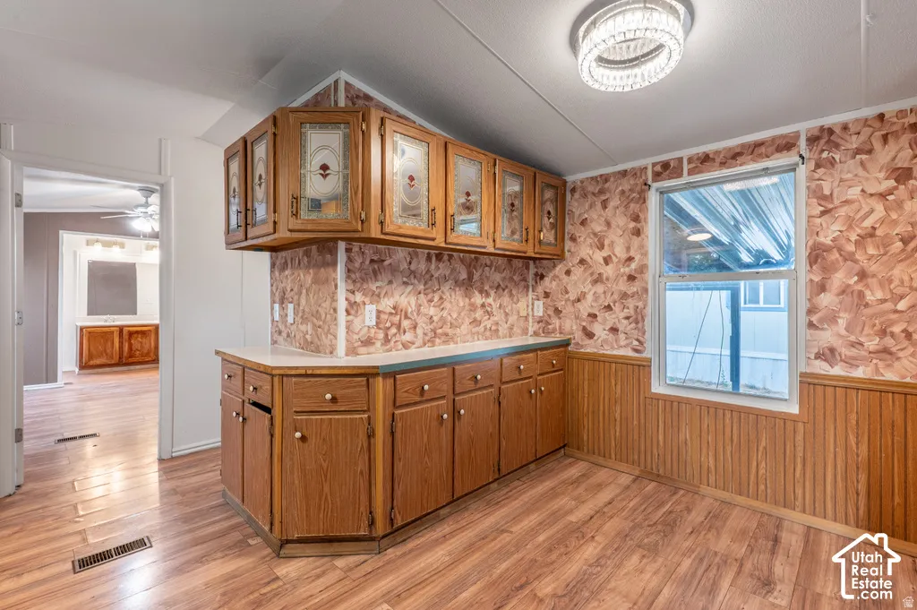 Wood-finish flooring with wood-paneled wainscoting, a built-in cabinetry unit, and an overhead lighting fixture