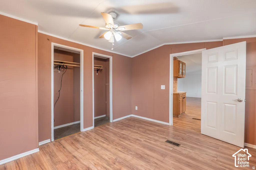 Wood-finish flooring throughout, ceiling fan, and two open closet spaces