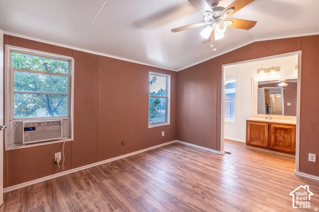Wood-finish flooring, ceiling fan with integrated lighting, natural light through multiple windows, and a built-in vanity with cabinetry and overhead lighting