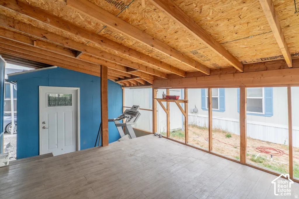 Covered outdoor space featuring exposed wood beams and a wood-finish flooring