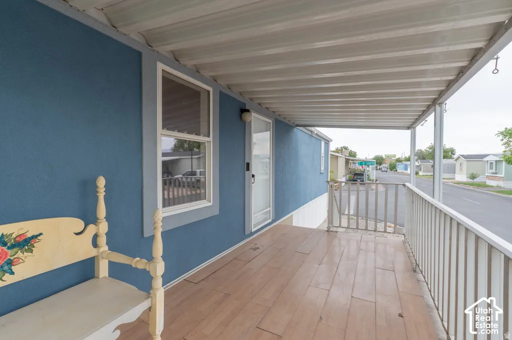 Covered porch with wood-finish flooring, white railing, and blue exterior siding