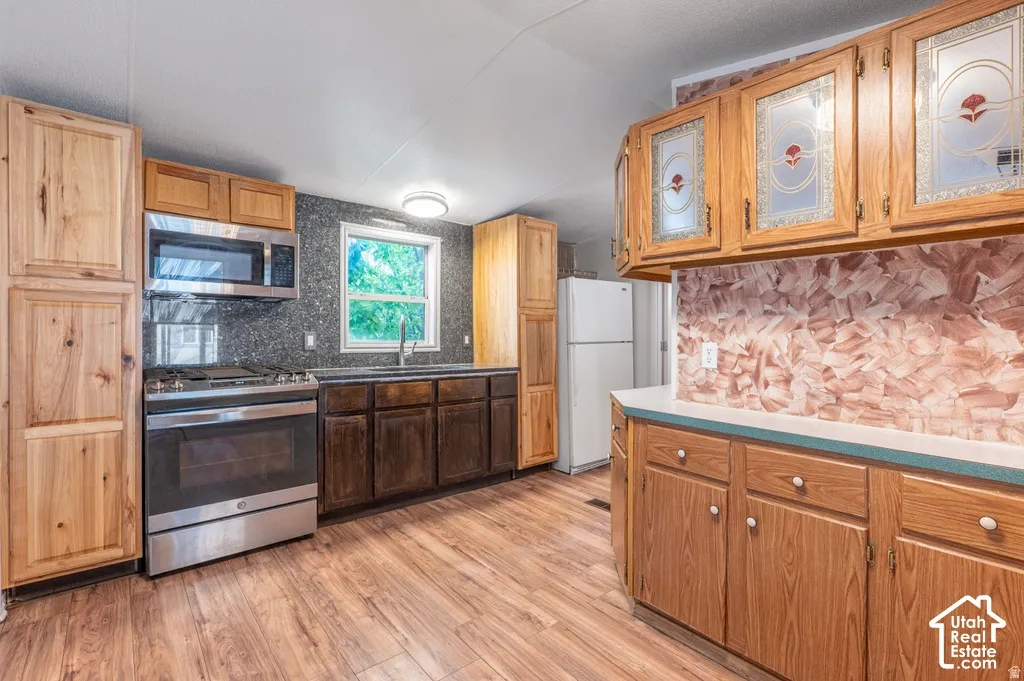 Kitchen featuring wood-finish flooring, stainless steel range with overhead microwave, and varied wood cabinetry