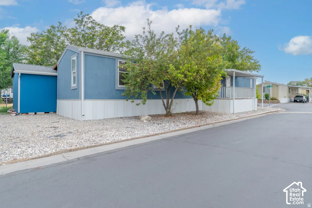 Blue exterior siding with white trim, covered porch, gravel landscaping, and a detached storage shed