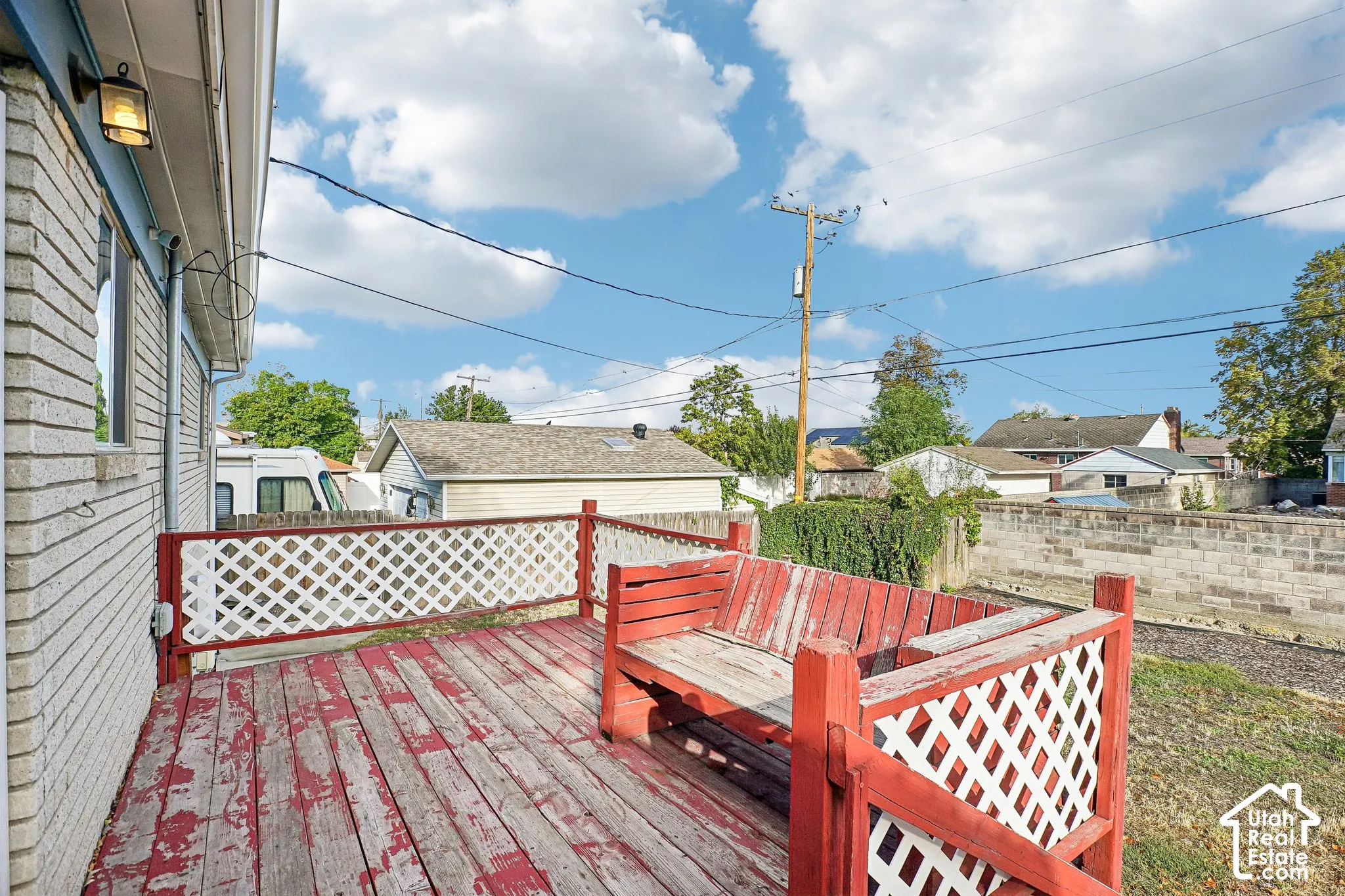 Exterior deck with built-in seating, white lattice railing, and a side-mounted wall light