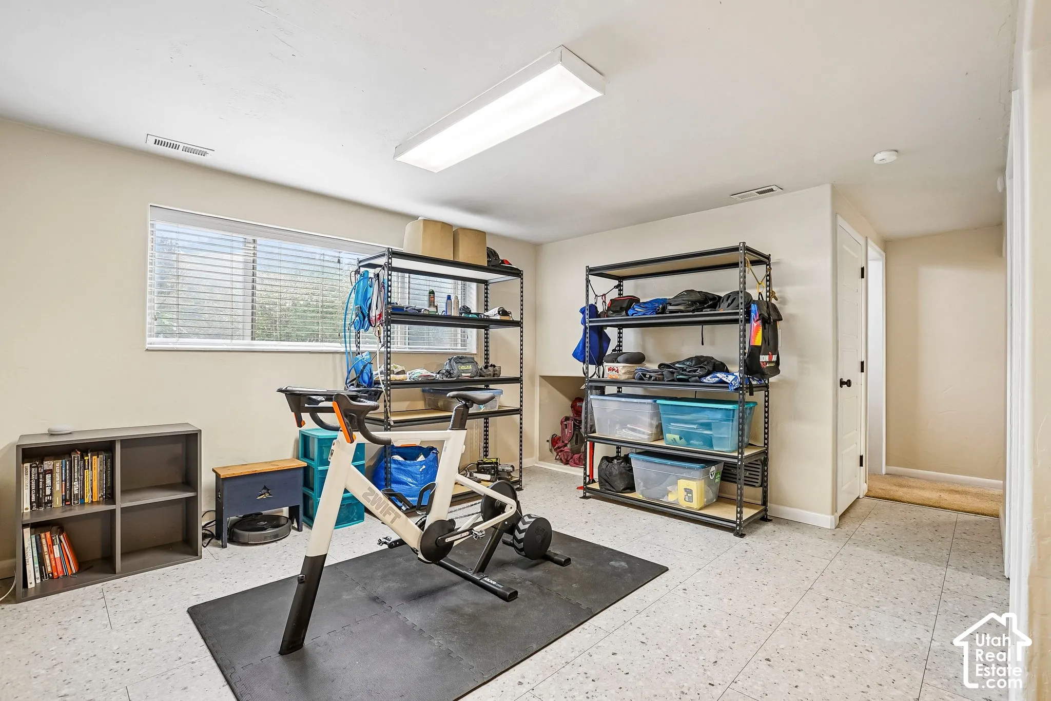 Recessed window with blinds, large overhead lighting, built-in shelving unit, and hard surface flooring