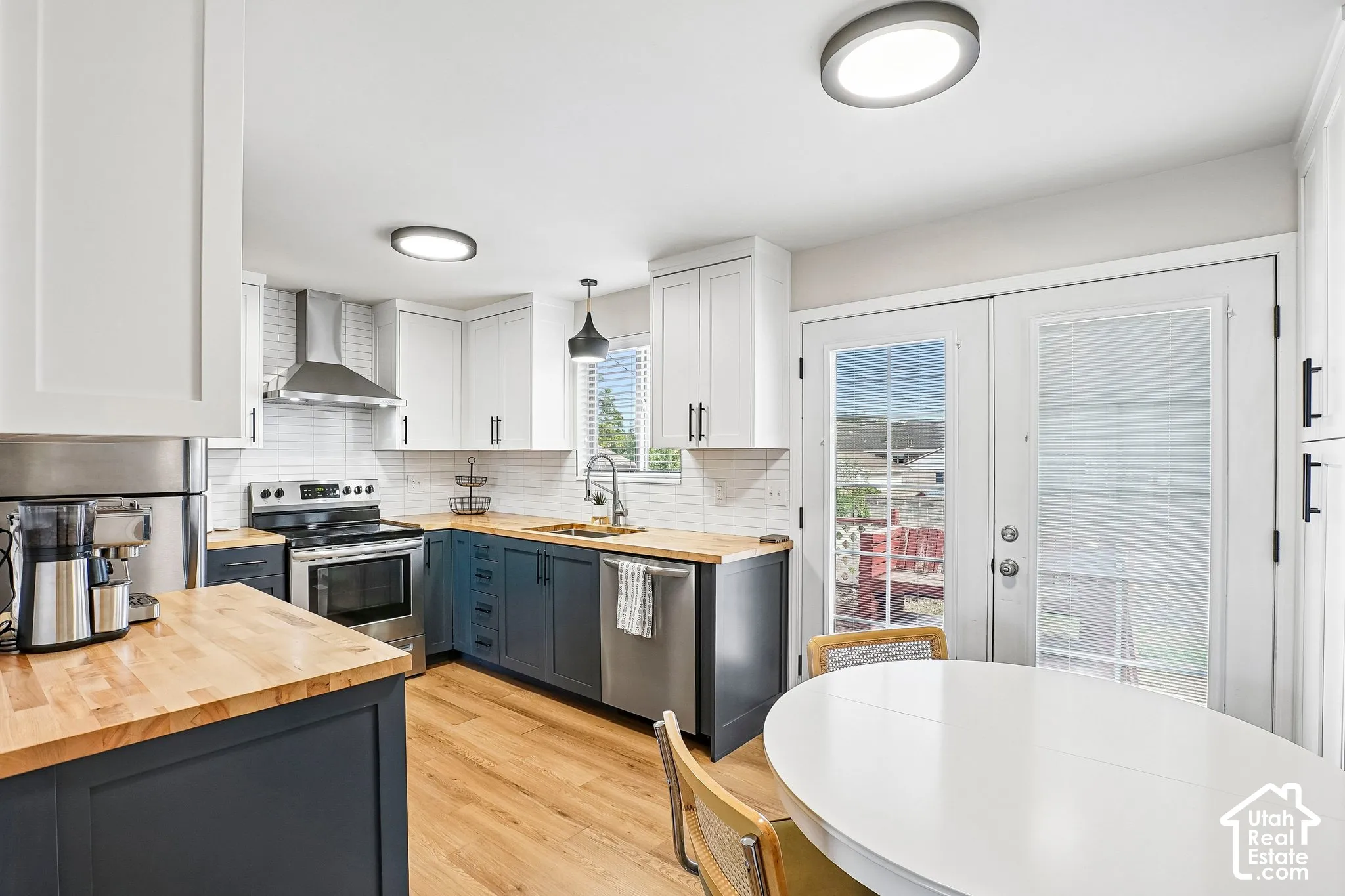 Kitchen featuring stainless steel appliances, wood-finish countertops, white subway tile backsplash, two-tone cabinetry, and wood-finish flooring
