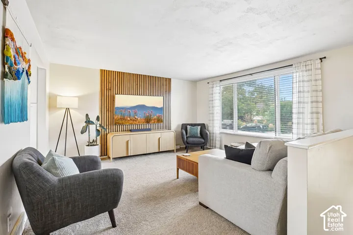 Light-colored carpeting, a large picture window, and a wood-slat accent wall with a built-in media console