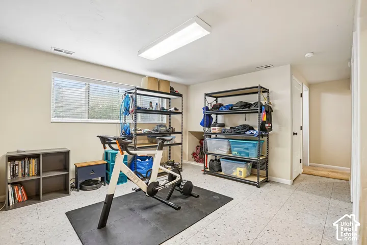 Recessed window with blinds, large overhead lighting, built-in shelving unit, and hard surface flooring