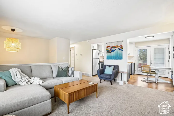 Open-concept living area with carpet flooring, a decorative pendant light fixture, and a partial wall separating spaces