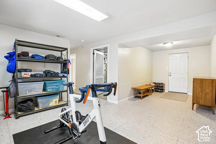 Spacious room with light-colored flooring, recessed lighting, and a white paneled door