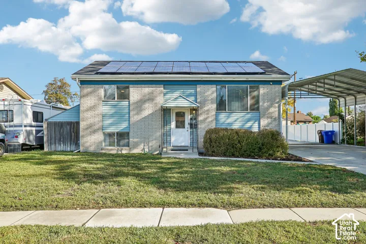 Light brick exterior with blue siding accents, solar panels, and a covered carport