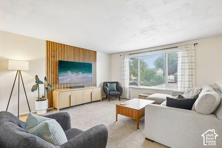 Living area featuring a slatted wood accent wall, broad window with blinds, and light-toned wall finishes