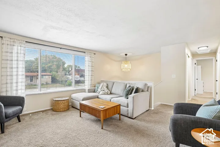 Expansive window with blinds and drapes, light neutral wall paint, and recessed lighting in the hallway