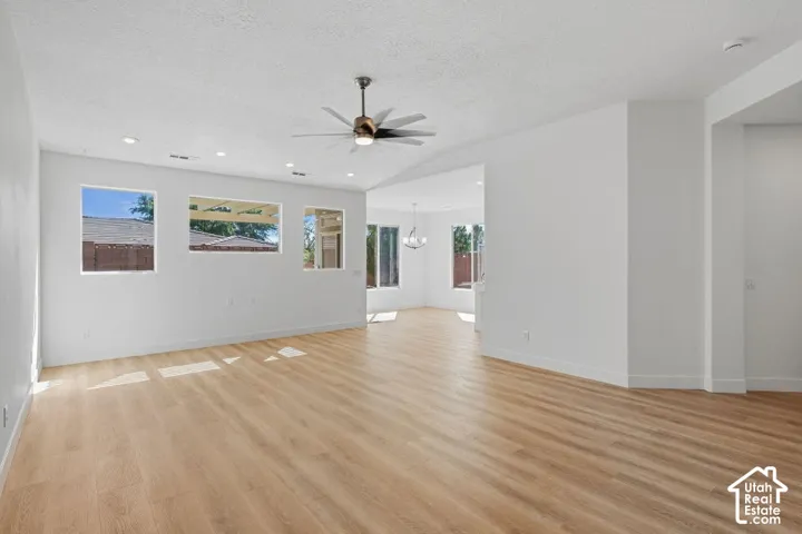 Spacious room with wood-finish flooring, white walls, and multiple windows