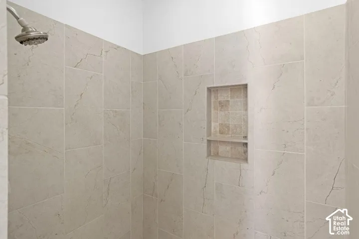 Shower enclosure with large format stone-finish wall tile, a recessed niche with mosaic tile accent, and a brushed nickel showerhead