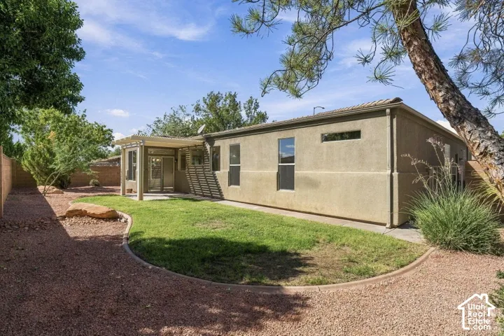 Stucco exterior with a covered patio, dual-pane windows, and a gravel pathway