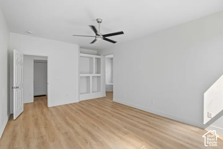 Wood-finish flooring throughout, modern ceiling fan, built-in shelving, and neutral wall finishes