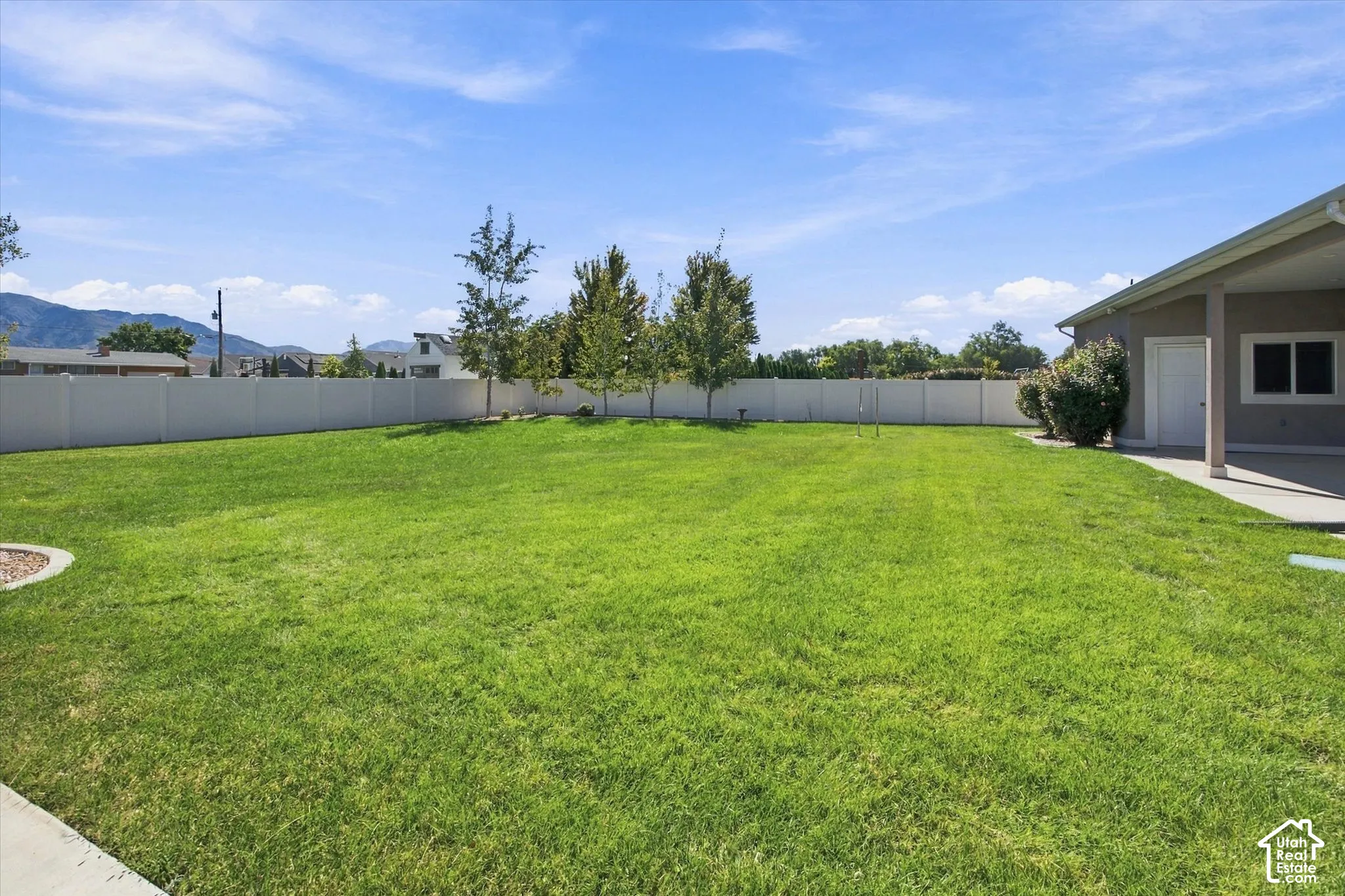 Expansive maintained .55 acres yard with a privacy fence, mature trees, and a covered patio area