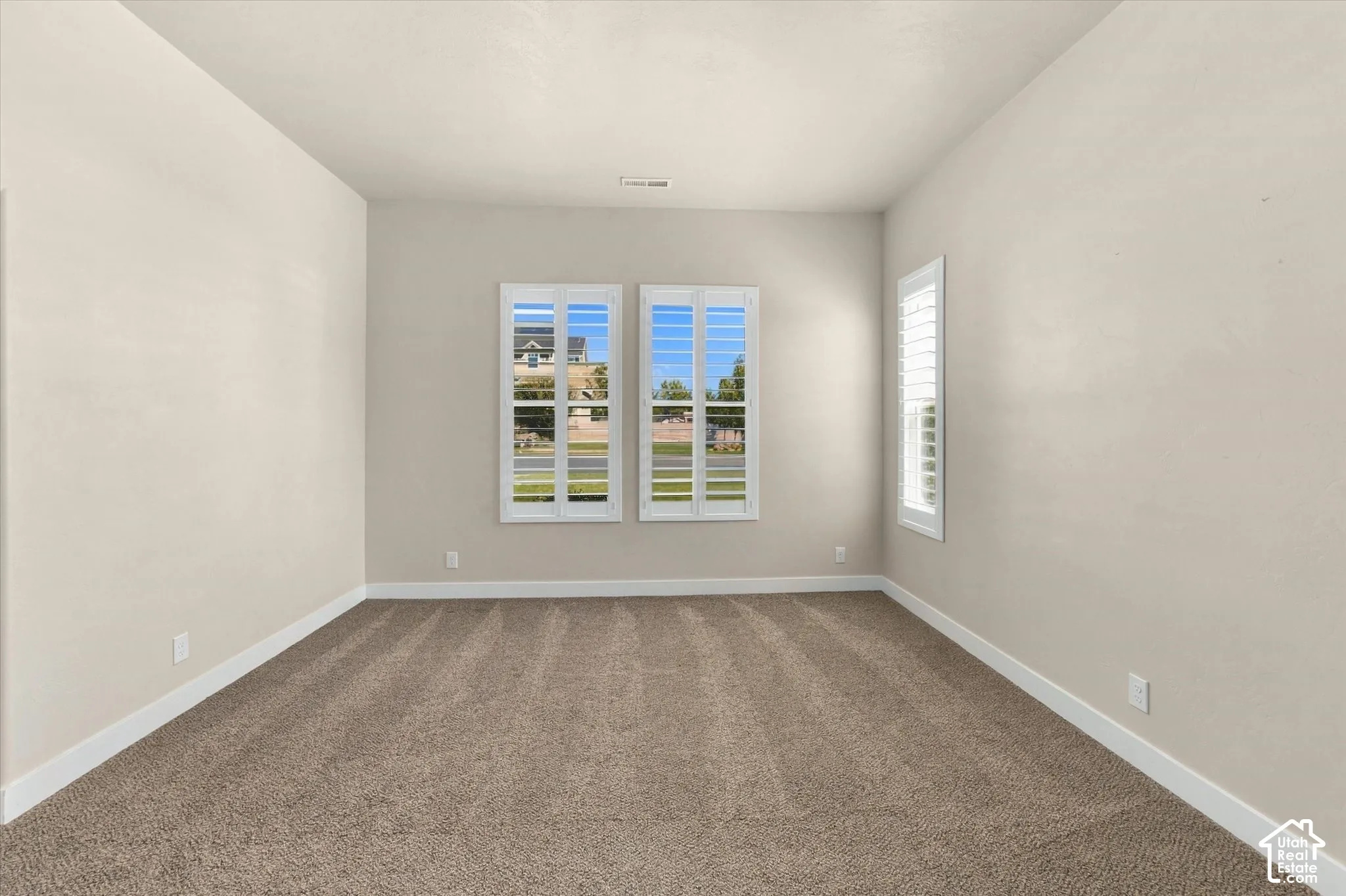 Planted shutters on multiple windows, neutral wall tones, and carpeted flooring